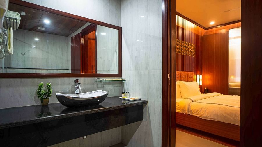 A modern bathroom at Mansha Palace features a sleek countertop with a vessel sink, a large mirror, and an open doorway to the bedroom.