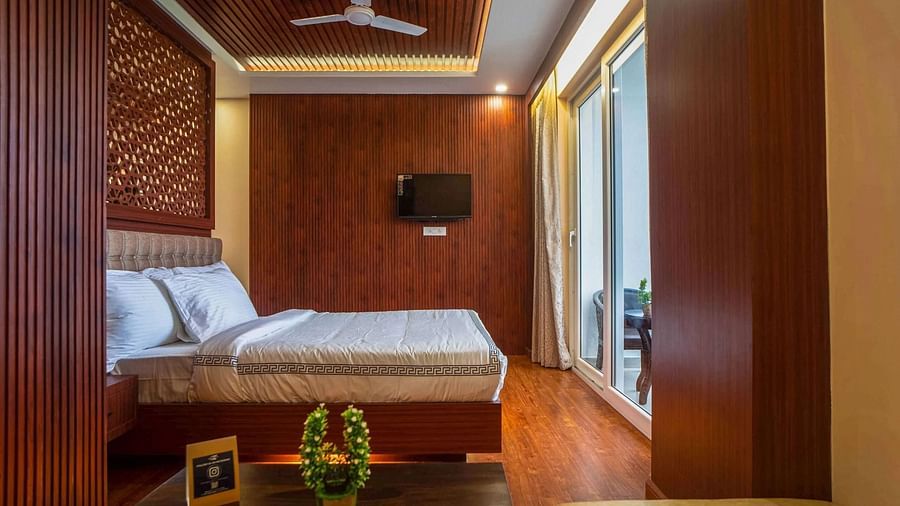 A stylish room at Mansha Palace offers a comfortable bed, a coffee table, a TV, and balcony access.