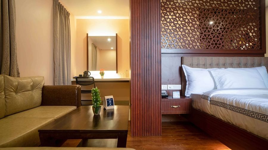 A well-appointed suite at Mansha Palace features a comfortable bed, a seating area with a coffee table, and a mirror.
