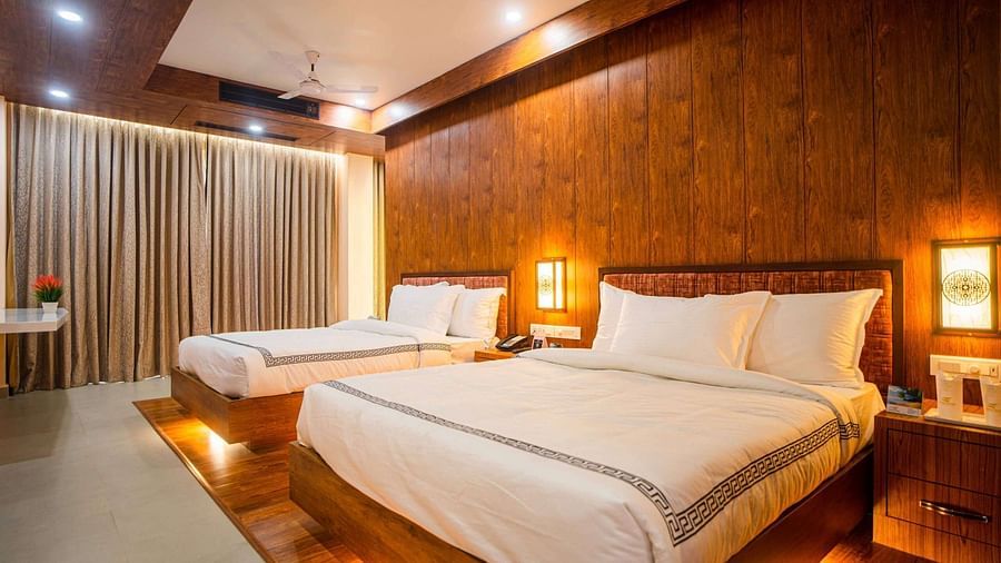 The comfortable rooms at Mansha Palace offer two beds, warm wooden accents, and a strategically placed opening that provides a peek into the bathroom.