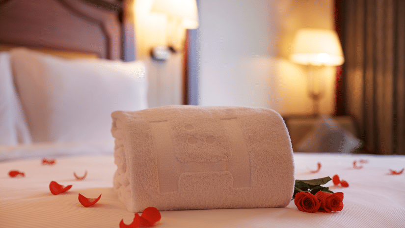Towel art and flower petals on the bed with dim lights at day stay hotel in chennai.