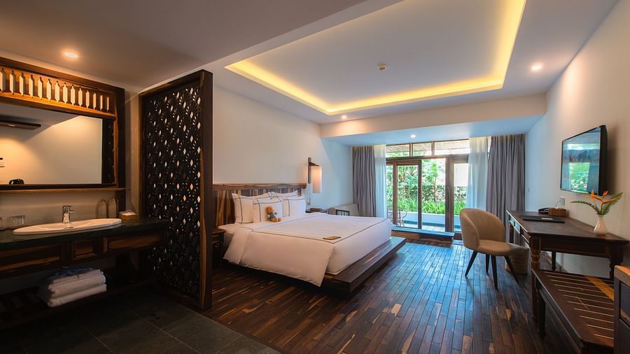 A hotel room with a king size bed, a work desk, a chair and a wall mounted television - Alibu resort Nha Trang