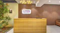 Reception area of VITS Select Nashik Hotels & Resorts featuring the logo of the property on the other side of the reception desk and a plant next to it