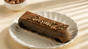 slice of peanut butter eclair  topped with chopped nuts on a white plate, with a bowl of nuts in the background Gemini Continental