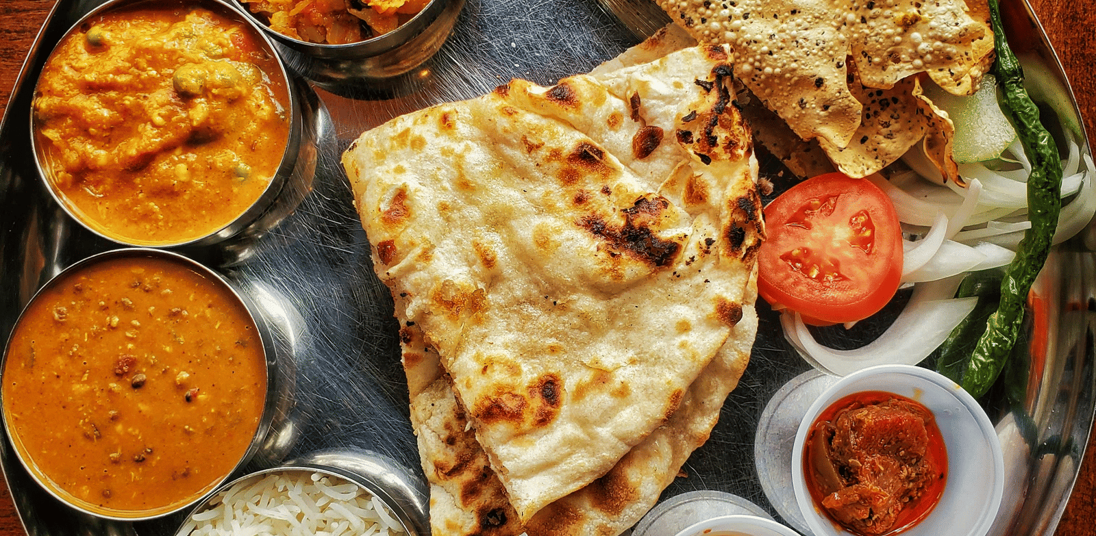 A neatly arranged plate with several Indian delicacies served.