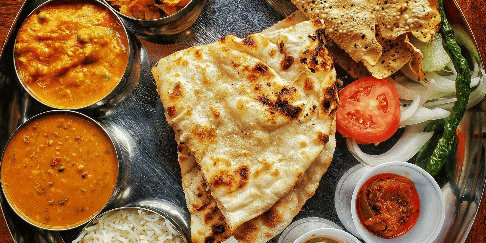 A neatly arranged plate with several Indian delicacies served.