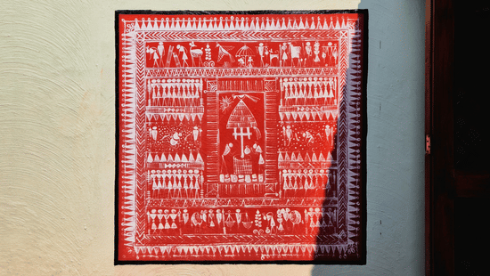 A vibrant Warli painting on an outdoor wall, featuring intricate tribal figures and geometric patterns under natural sunlight.