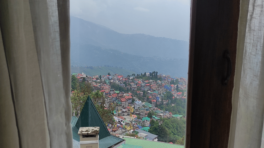 Balcony view from the Executive Suite at Cedar Inn, featuring an open doorway with curtains and a partial view of hillside buildings and mountains beyond.