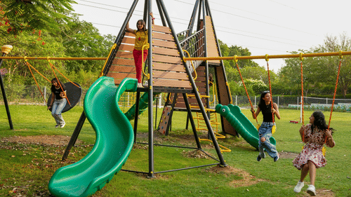 An overview of the children's play area with kids on the swing at Karma Lakelands.