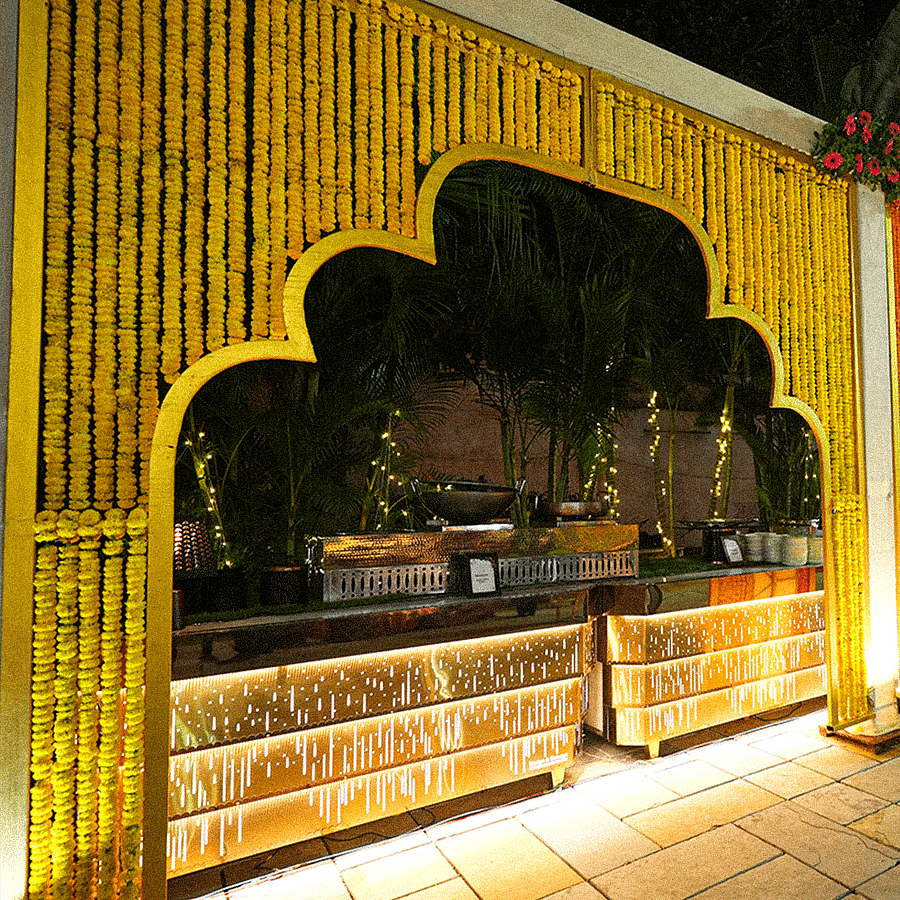 alt-text Beautifully lit outdoor food event decor featuring a yellow marigold archway and a traditional setup at night