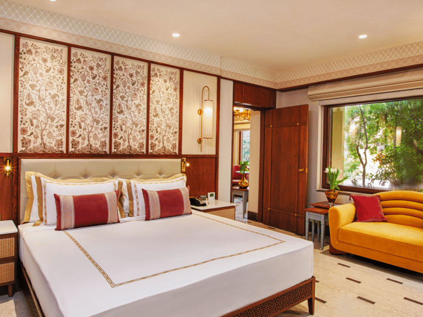 Room with double bed, cushioned seating, and decorative wall panels at Heritage Village Resorts & Spa, Manesar.