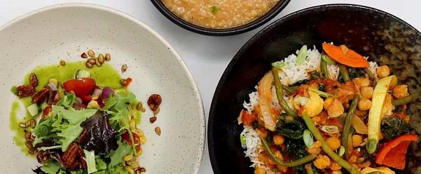 Top-down view of three dishes, including a salad with nuts, a lentil soup with lemon, and a stir-fried vegetable dish with rice.