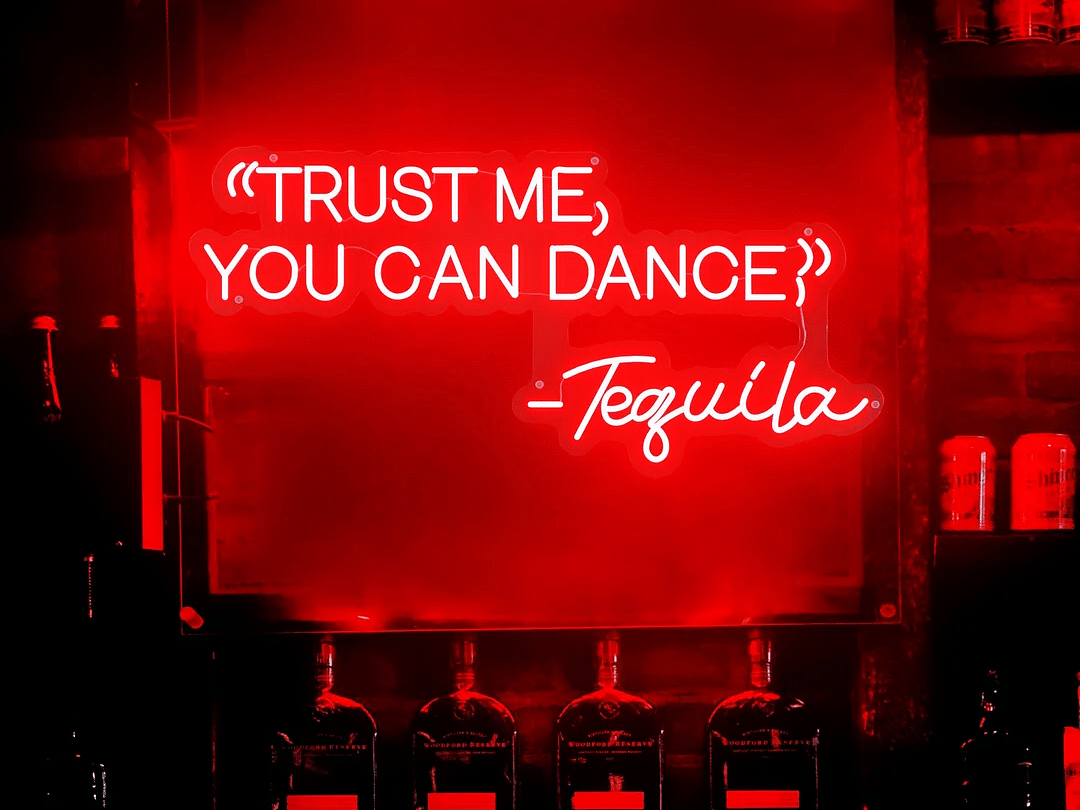 An image of a poster reading Trust me you can dance on the board illuminated by red lights - Motel Divine International, Roorkee