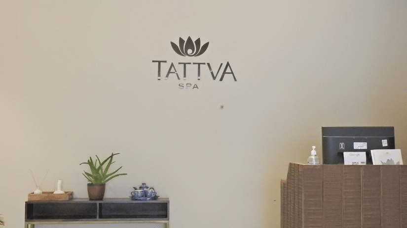 The signage of tattva spa on the wall with the reception desk below at  Polo Hotel Agartala