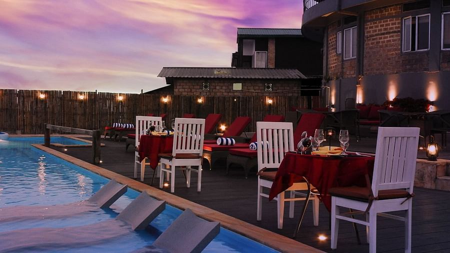 An image of dining tables and chairs set by the poolside at Polo Orchid Resort, Cherrajunji
