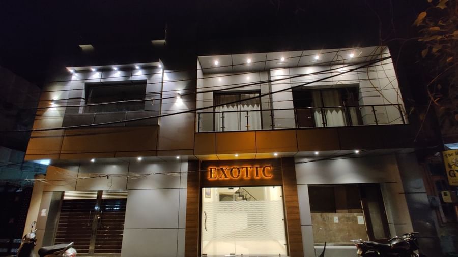 An exterior shot of Hotel Exotic Amritsar at night, showing the illuminated signage and the modern facade of the building.