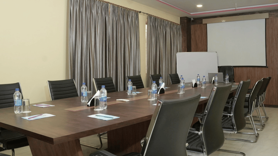 A long wooden boardroom table set with water bottles and stationery in a meeting room at the Ram Bhawan Ram Yamuna Prasad Hotel and Resort.