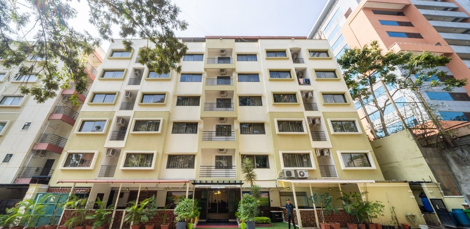 A modern multi storey building with numerous windows stands against a clear sky, showcasing the exterior of Lords Midtown Suites.