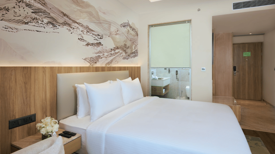 Premium Double Bed Room at Riviera Sarovar Portico, Pathankot, featuring a king size bed, wall-mounted television, wooden flooring, work desk, wardrobe, and an ensuite bathroom.