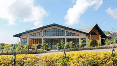 The Mausmai Ballroom features a grid-patterned glass facade, flooding the space with natural light and offering panoramic views of the lush garden outside.