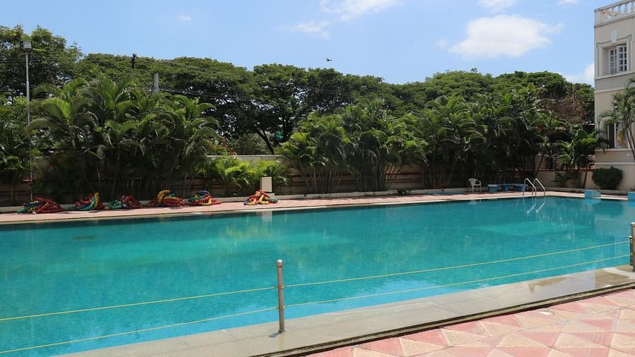 Outdoor rooftop swimming pool at Jenneys Residency, surrounded by lush trees and open sky for a serene escape