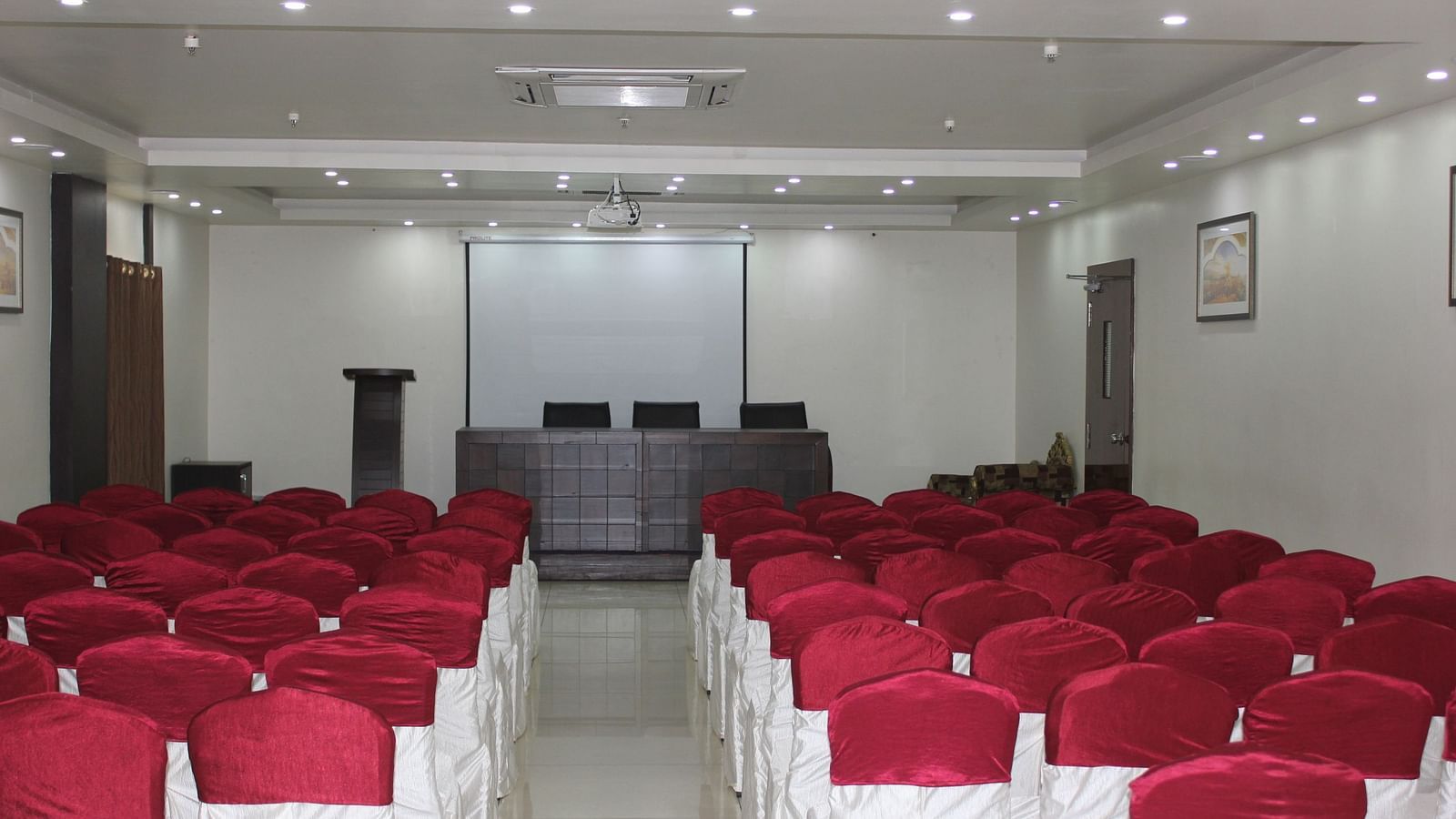Image of Swathi Hallwith chairs arranged and lights on the ceiling at Hotel Green Apple