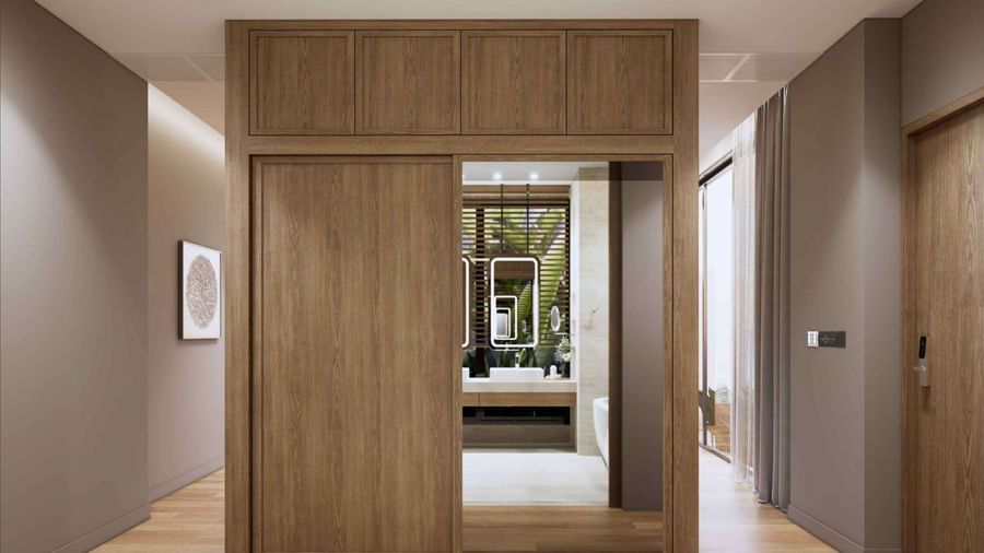 The entrance to a villa room at Ramada Resort by Wyndham Khao Lak, with a large wooden wardrobe and a mirror reflecting the bathroom.