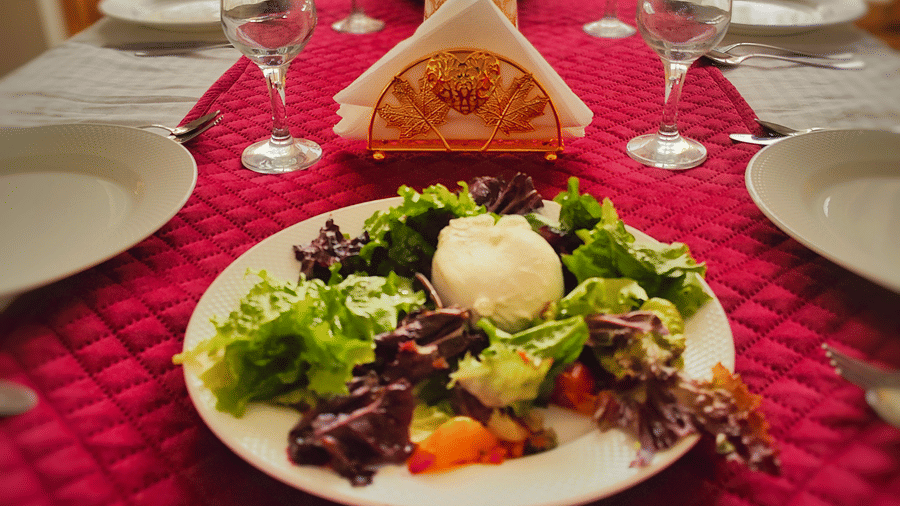 A vibrant green salad served on a table decorated with a red quilted runner and glassware at Indus Serenity Retreat.