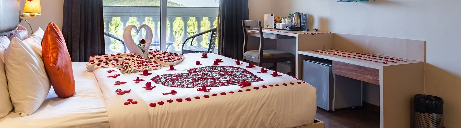 Side view image of a room with a bed and flower petals arranged on the bed and a television in front at Calux Grand Baga.