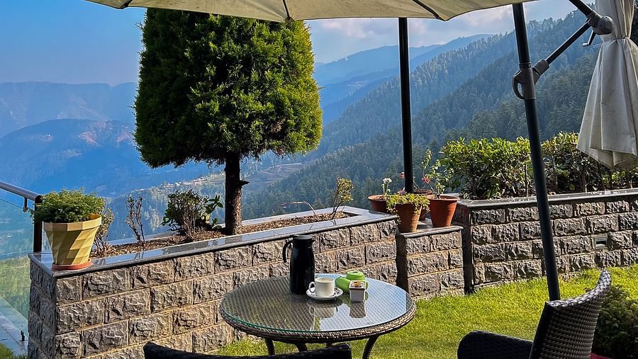 Outdoor dining setup under a parasol with majestic mountain views at Aranya Himalayan Retreat, Mashobra