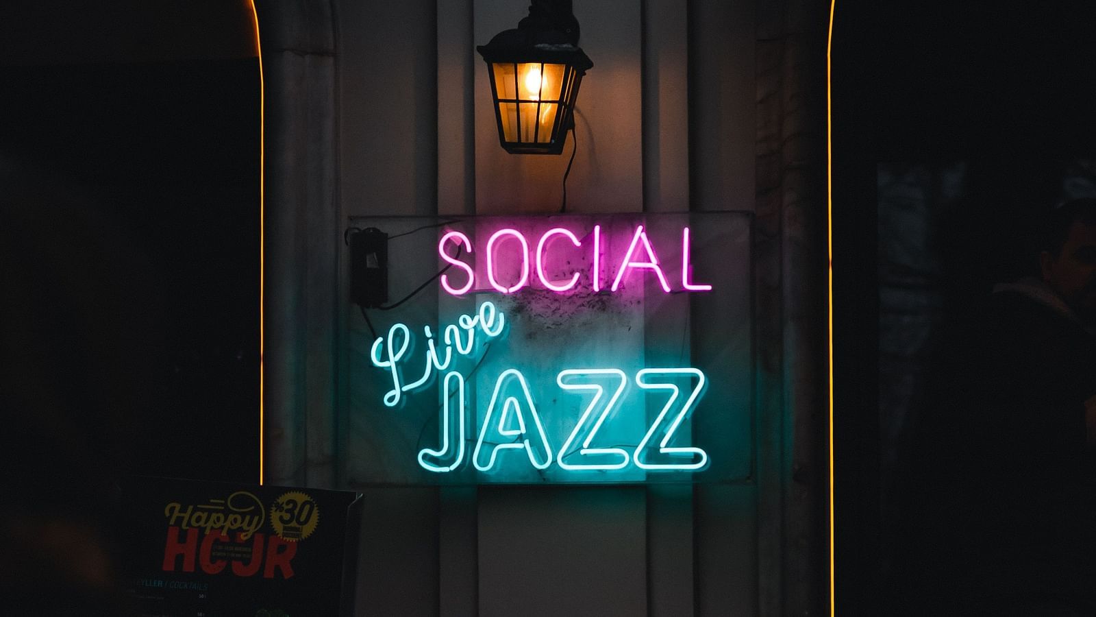 a neon sign with the words Social, Live, Jazz written and a fancy street light above it
