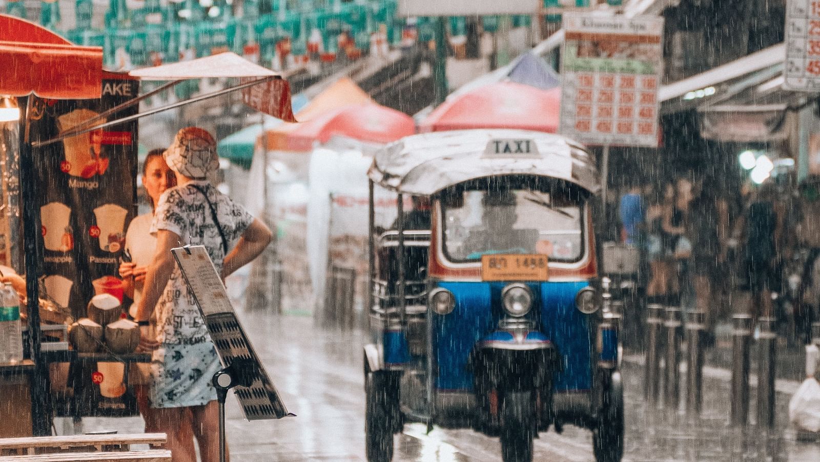 an image of the Khao San Road captured when it is raining and a tuk-tuk can be seen