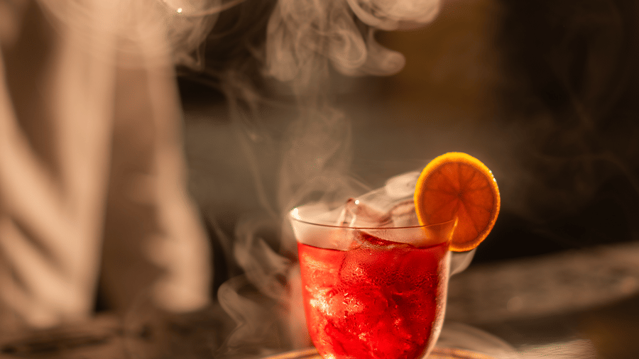 Drink in a glass with smoke rising and garnish on top at Origyn bar, Merlis Hotel, Coimbatore.