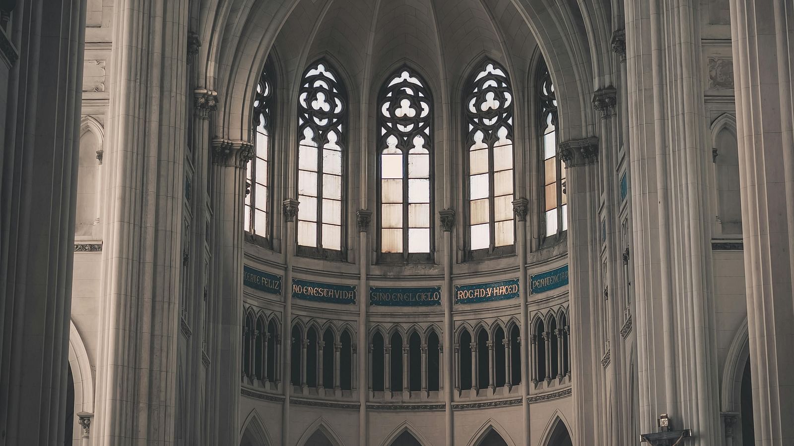 Interior of a grand cathedral with towering arches and stained-glass windows.