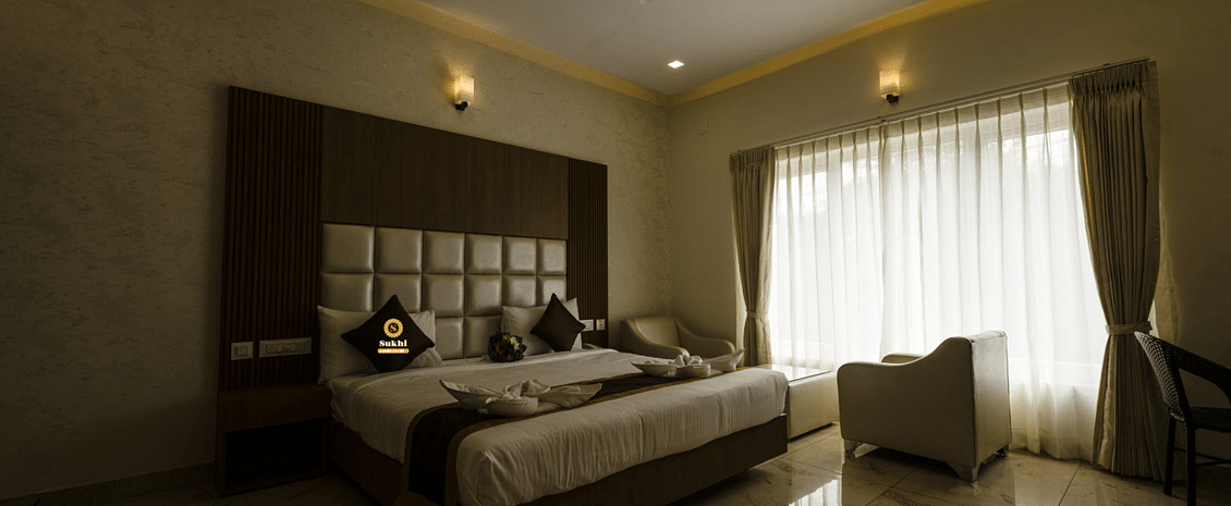 Suite featuring a king size bed, a chair, and sheer curtains. - Sukhi - A Luxury Stay Inn, Chikkamagaluru