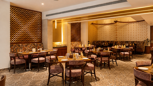 Indoor dining area at Pride Premier Pune with tables, chairs and contemporary décor.