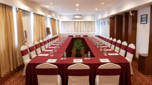 Boardroom with U-shaped seating and white chair covers at Pride Premier Pune, arranged for meetings and presentations.