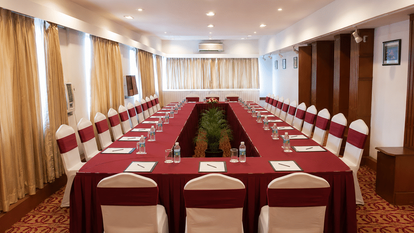 Boardroom with U-shaped seating and white chair covers at Pride Premier Pune, arranged for meetings and presentations.
