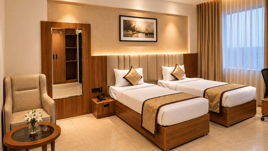 Well-lit guest bedroom with twin beds, armchair, and modern decor at Bhavani's Vista By Icon, Hosur.   