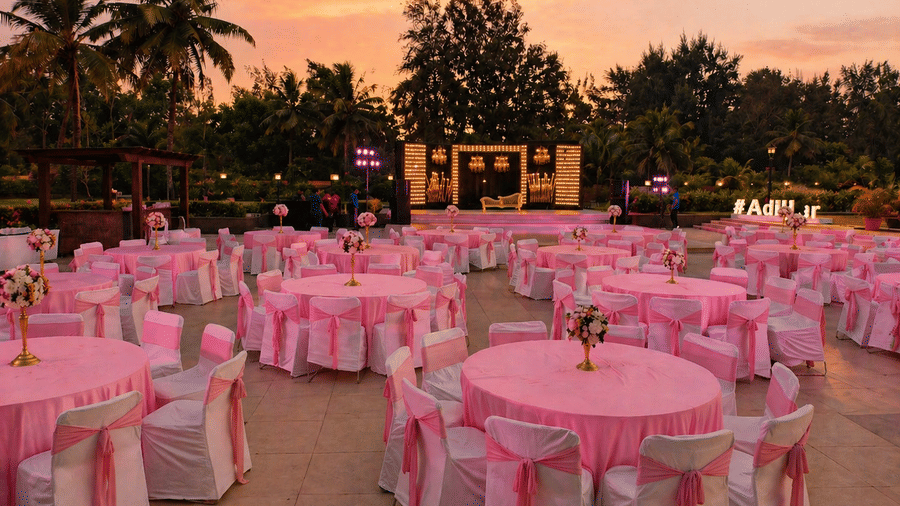 Outdoor lawn event venue decorated with pink tablecloths and draped seating at Kenilworth Resort & Spa, Goa.