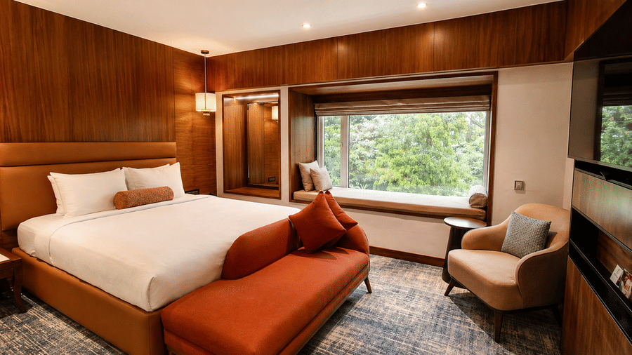 Contemporary room at Pride Premier Pune with a king size bed, window seating and wooden interiors.