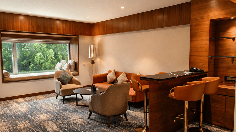 Suite workspace at Pride Premier Pune with a dining table, chairs, lounge seating and large window.