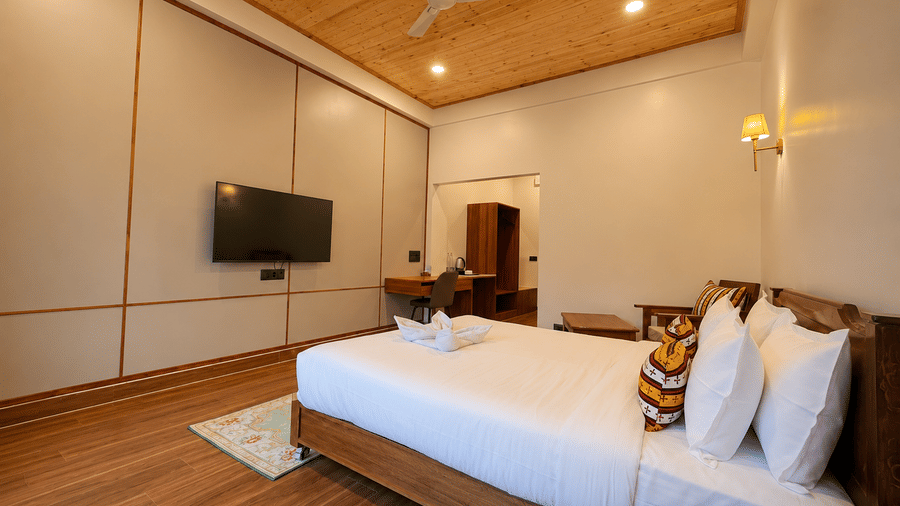 Double bed with white linens, bedside lamp, wall-mounted TV, and wooden ceiling at Summit Rungkhung Village Resort.