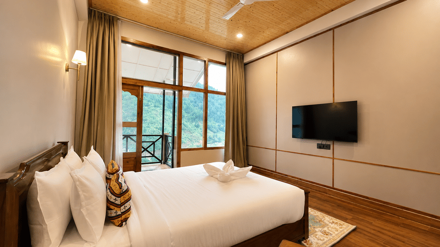 Bedroom with wooden bed, white linens, wall-mounted TV, and large window opening to a balcony at Summit Rungkhung Village Resort.