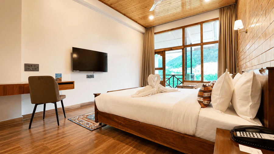 Double bed, wall-mounted TV, study desk, and large balcony window with curtains at Summit Rungkhung Village Resort.