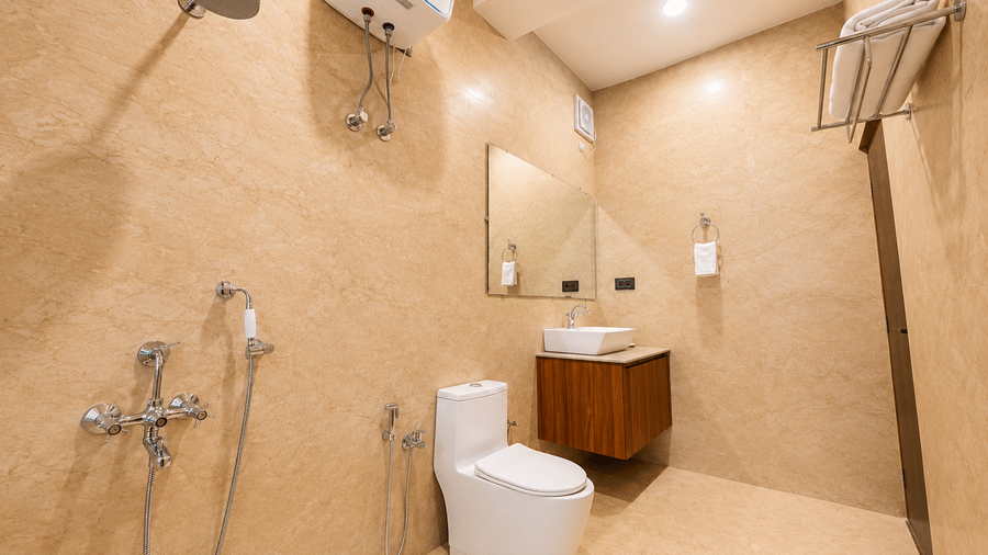 Modern bathroom with a toilet, wall-mounted shower fixtures, mirror, vanity sink, and water heater at Summit Rungkhung Village Resort.