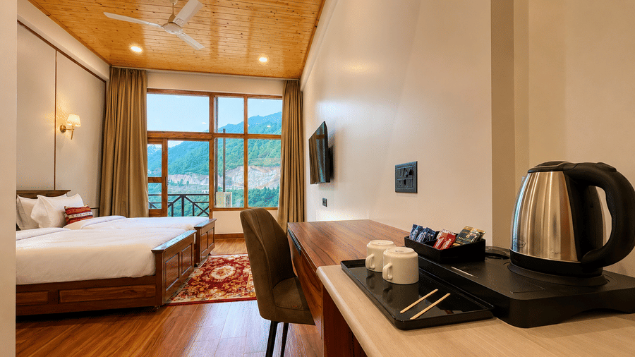Room with double bed, tea kettle station on desk, chair, and balcony window at Summit Rungkhung Village Resort