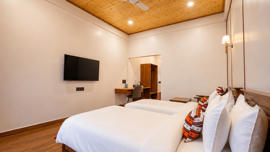 Twin beds with white bedding, wall-mounted TV, and study desk in a room at Summit Rungkhung Village Resort.