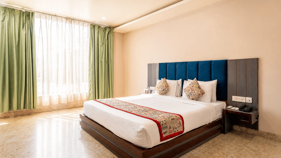 Comfortable bedroom with king size bed and floor-to-ceiling curtains at Bamboo Saa Mulberry Resort, Pushkar.