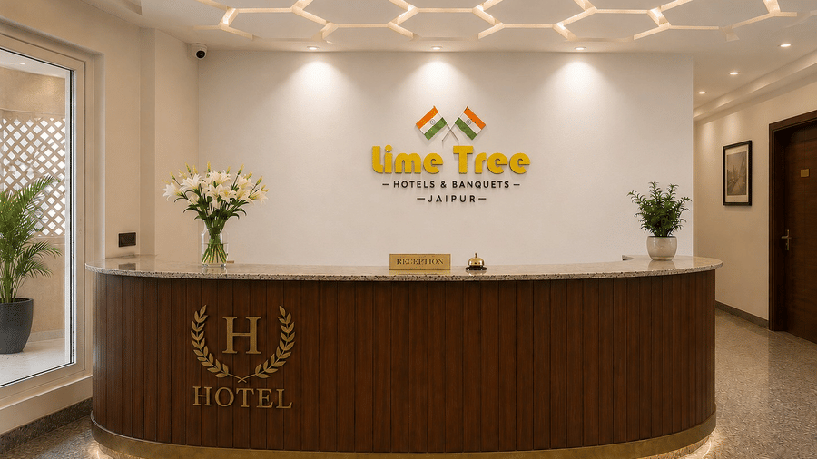 A modern hotel reception area featuring a curved wooden front desk, a white wall with the text Lime Tree, and a geometric honeycomb ceiling pattern.